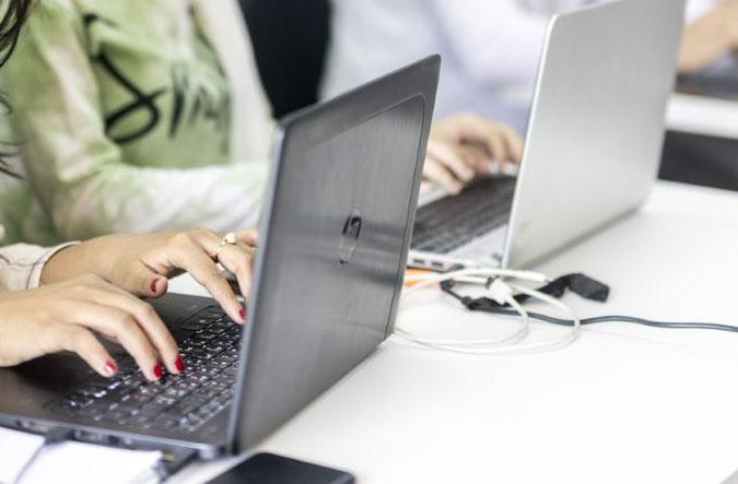  Weibliche Hände tippen auf der Tastatur eines schwarzen Laptops 